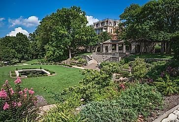 Lush landscaped garden in Murphys with stone terraces, green lawns, and a historic estate surrounded by trees.