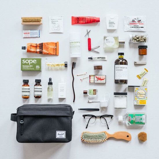 Travel toiletry essentials laid out with grooming items, skincare, and a toiletry bag