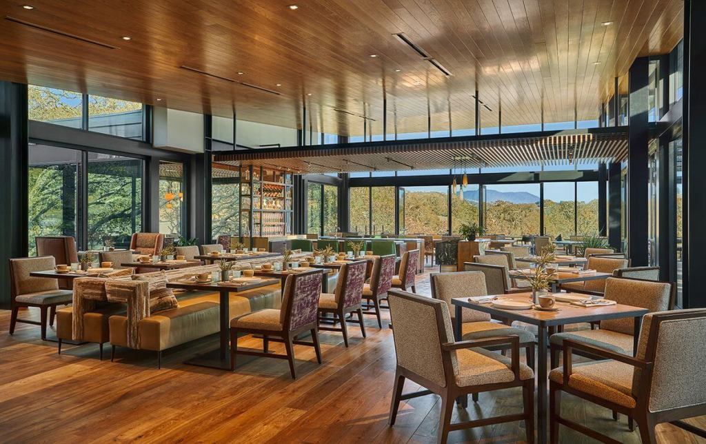 Elegant dining room at Hazel Hill with floor-to-ceiling windows, modern decor, wood accents, and scenic forest views