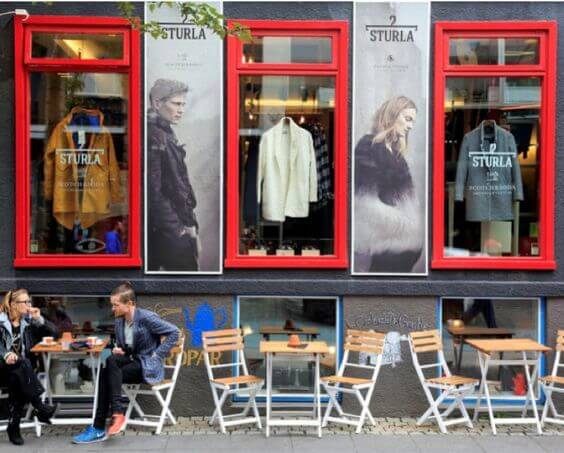 Outdoor café seating and fashion store with red-framed windows in Copenhagen.