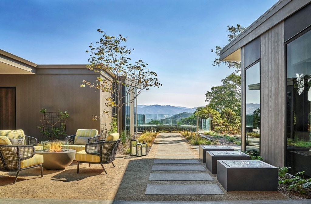 Modern outdoor lounge at Montage Healdsburg with fire pit seating, minimalist architecture, and scenic vineyard mountain views.