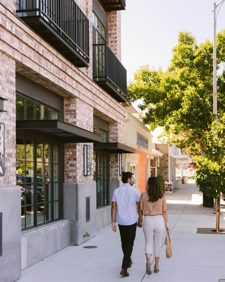 Couple walking hand-in-hand along a charming brick building street in Paso Robles, California.