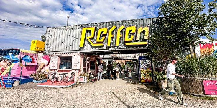 Entrance to Reffen street food market in Copenhagen with colorful signage and visitors walking by