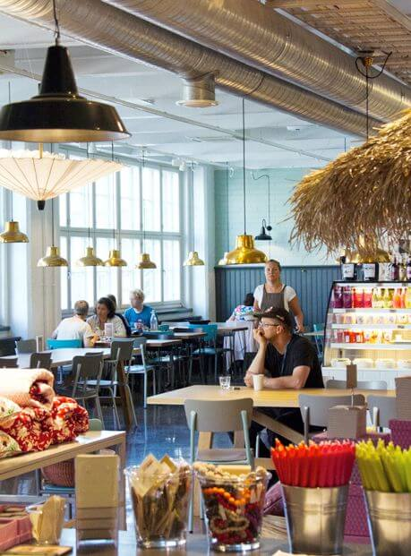 Bright and modern café interior in Helsinki with customers dining and colorful décor.