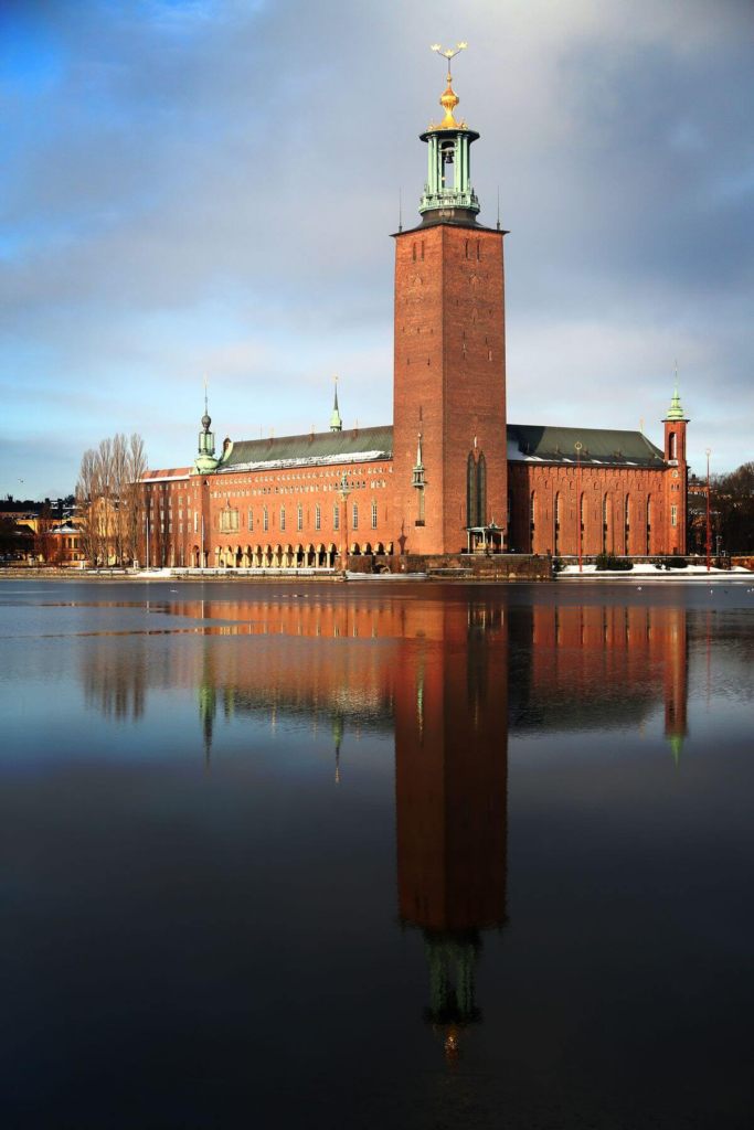 "Stockholm City Hall with reflection in water, showcasing its iconic tower and architecture.
