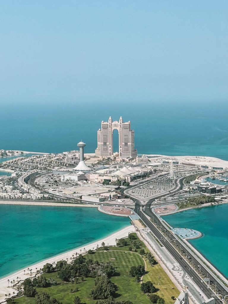 "Panoramic view of the Emirates Palace in Abu Dhabi with turquoise waters and surrounding cityscape."