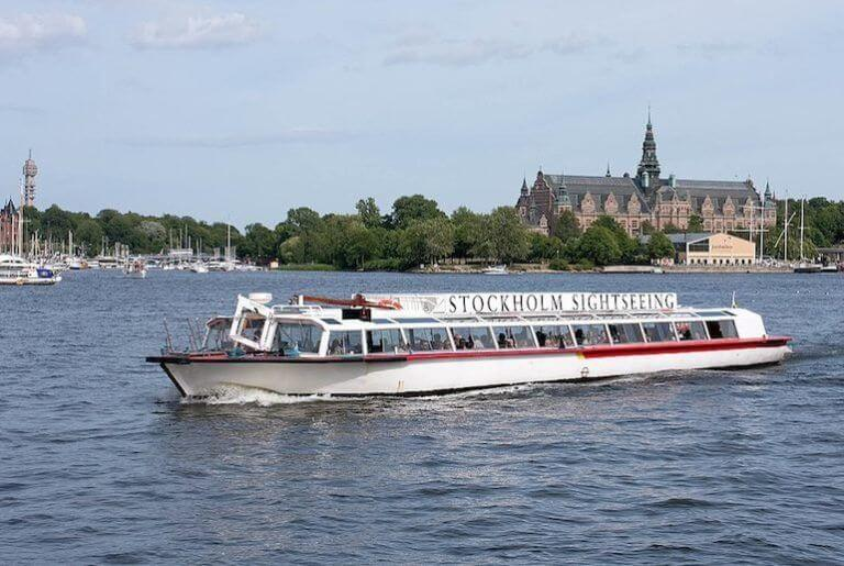 "Stockholm sightseeing boat cruising through the waterways with historic buildings in the background.