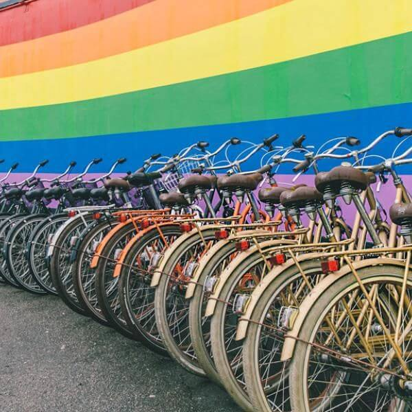 Row of colorful bicycles parked in Copenhagen against a rainbow wall