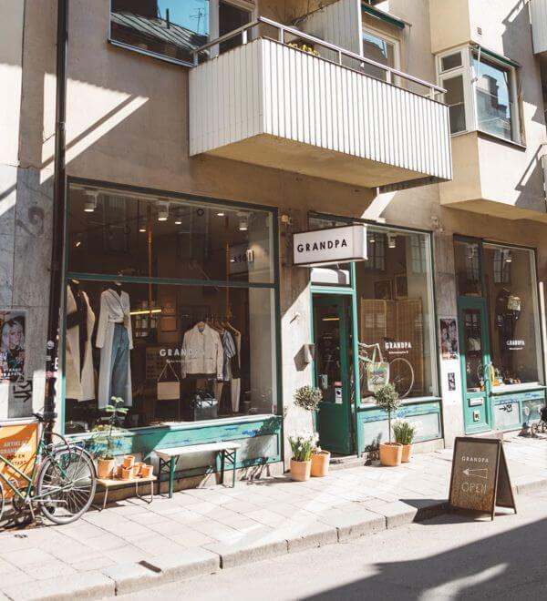 "Exterior of Grandpa store in Stockholm with a green entrance, window displays, and a sidewalk sign."