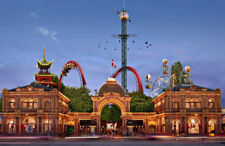 Entrance of Tivoli Gardens in Copenhagen at dusk with rides