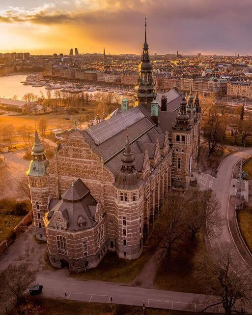 "Nordiska Museet in Stockholm with sunset lighting and city skyline in the background."