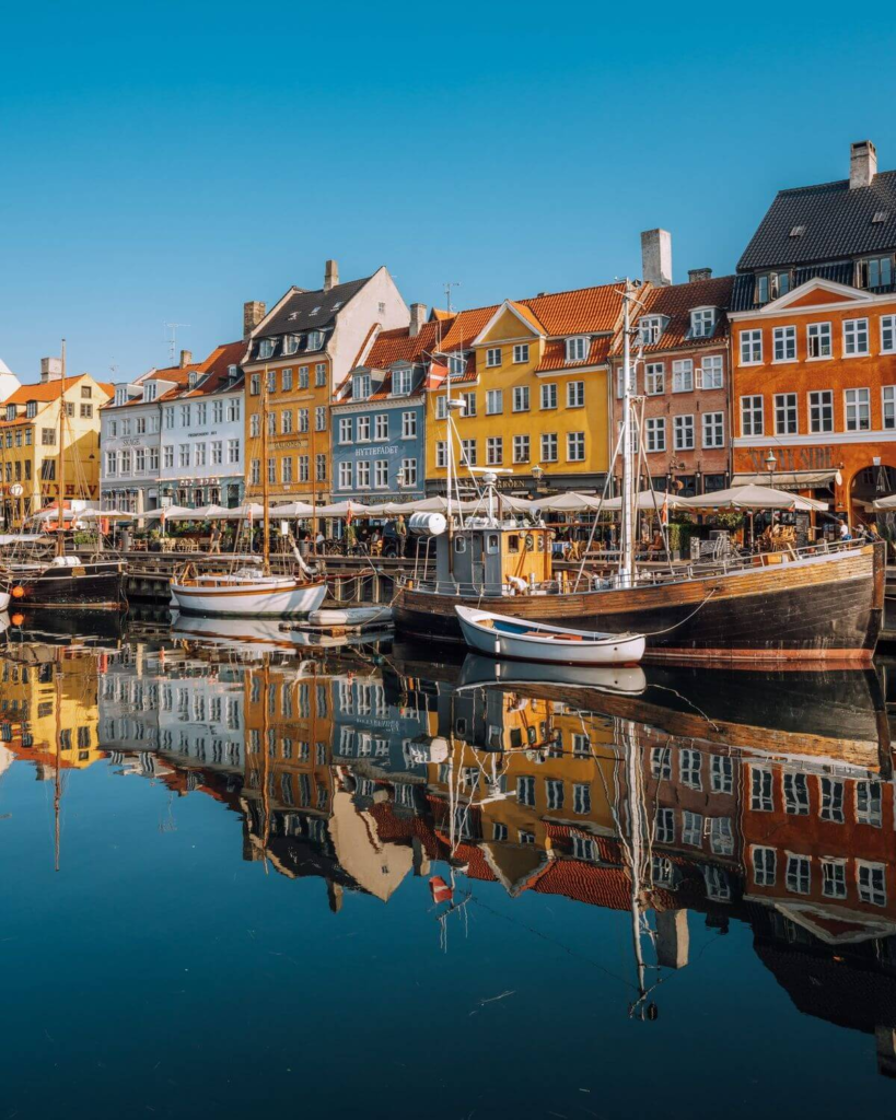 Colorful houses and boats reflecting in the canal at Nyhavn Copenhagen