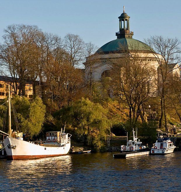 "View of Skeppsholmen island with boats and the circular dome of the building in the background."