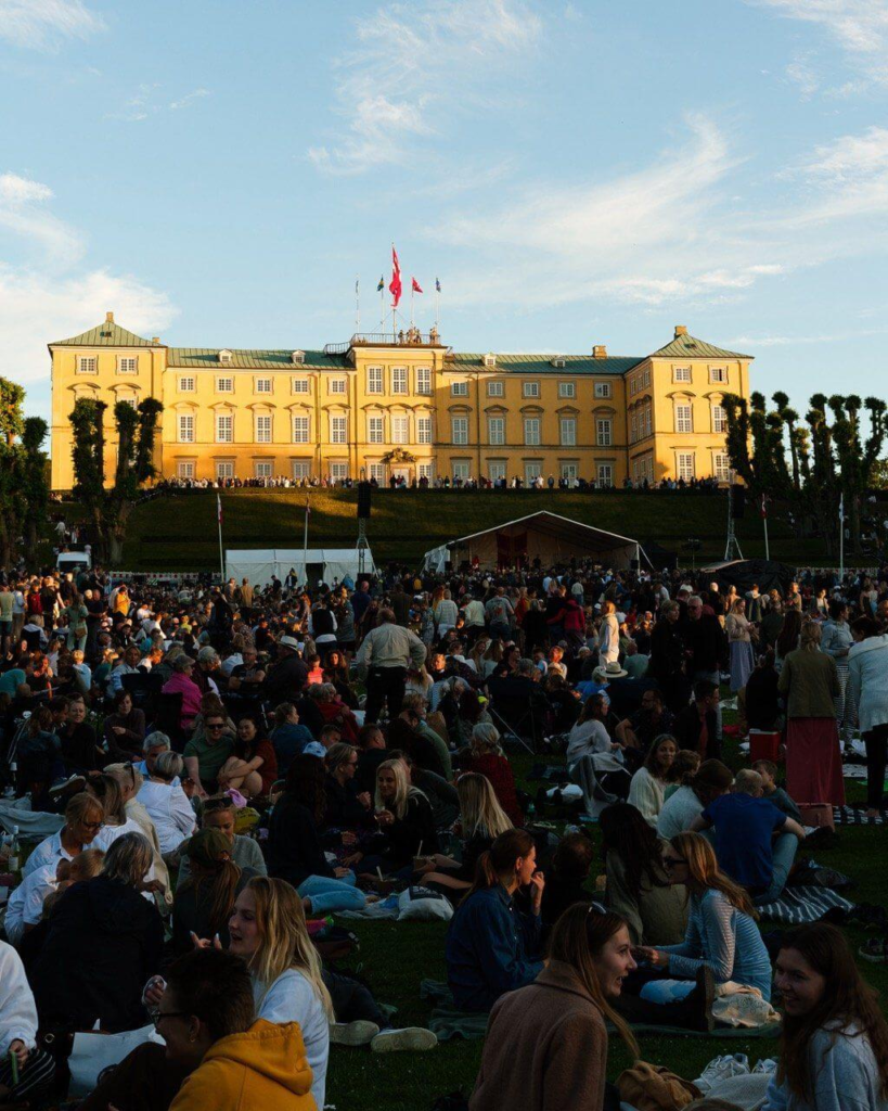 Crowd enjoying a summer festival at a historic palace in Denmark, showcasing Danish culture and lifestyle